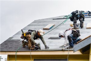 Men working on roof and nailing in the shingles