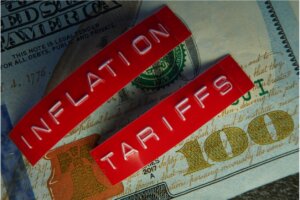 100 dollar bill with "inflation" and "tariffs" label on top